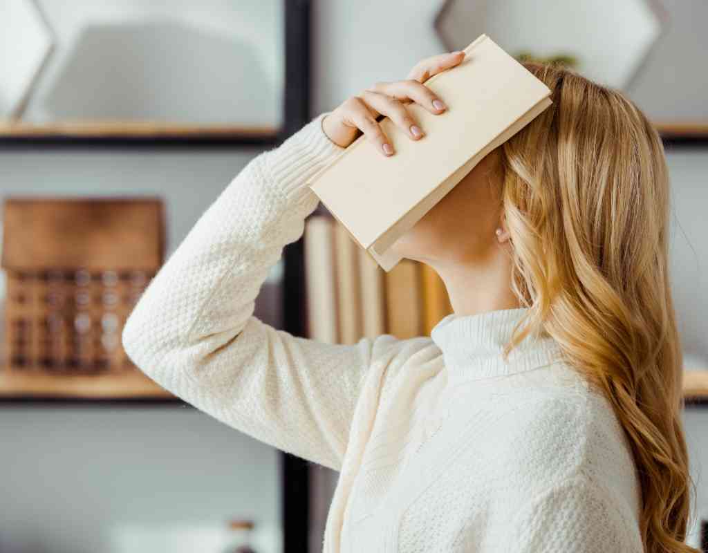 Woman in white with white book on face trying to be a better reader
