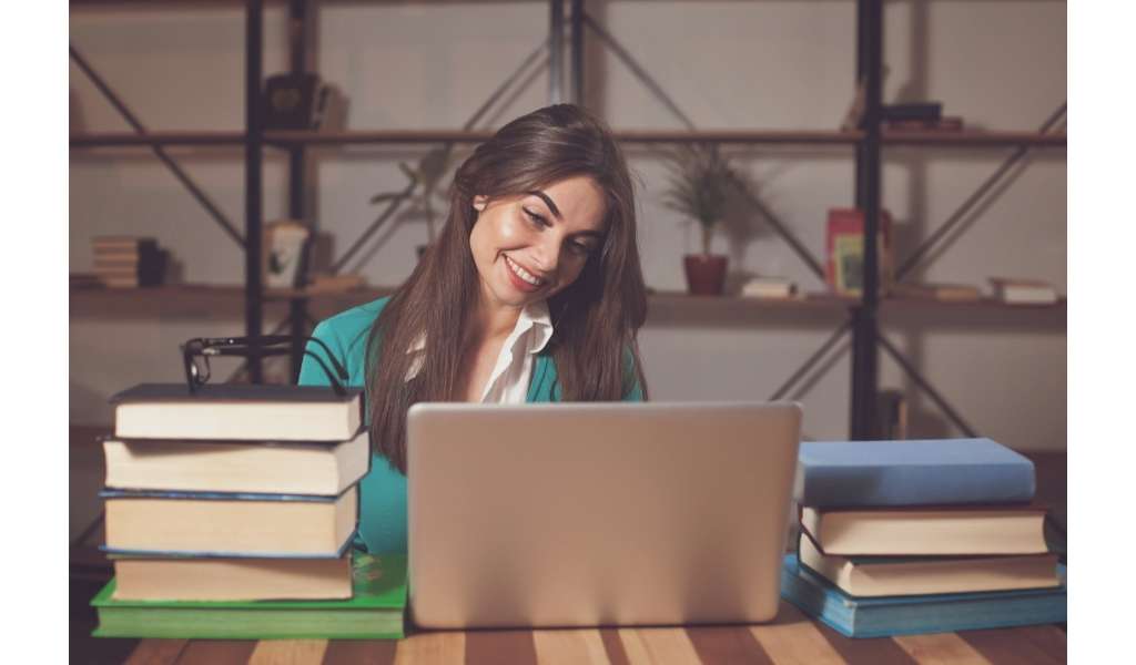 woman on laptop by books