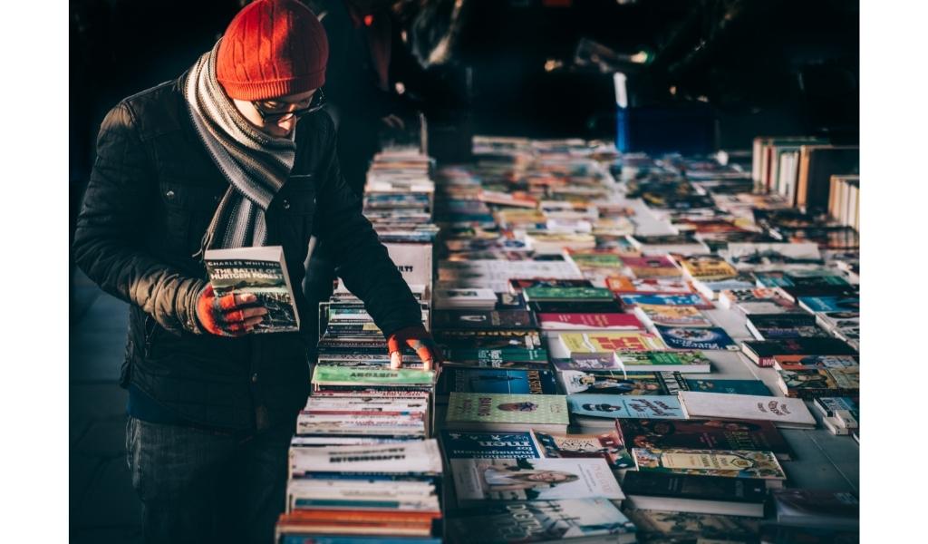 man picking books of different genres to help him read multiple books at once