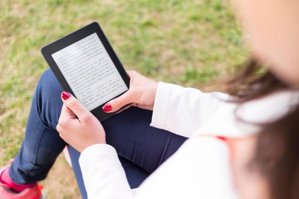 woman reading e-book on grass